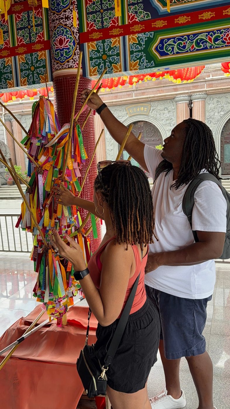 Brittney tying a wish ribbon at a colorful temple